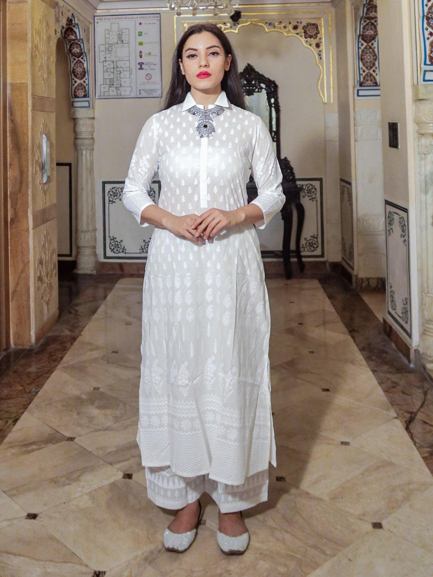 Woman in a white khari print cotton kurti with palazzo set featuring intricate embroidery