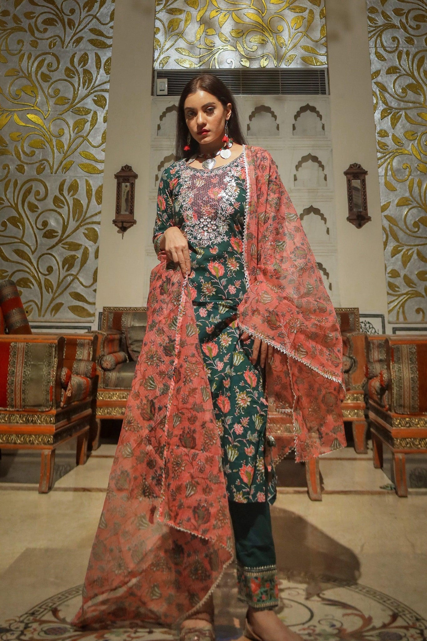 Woman in a green floral printed kurta pant set with a pink sheer shawl and floral design