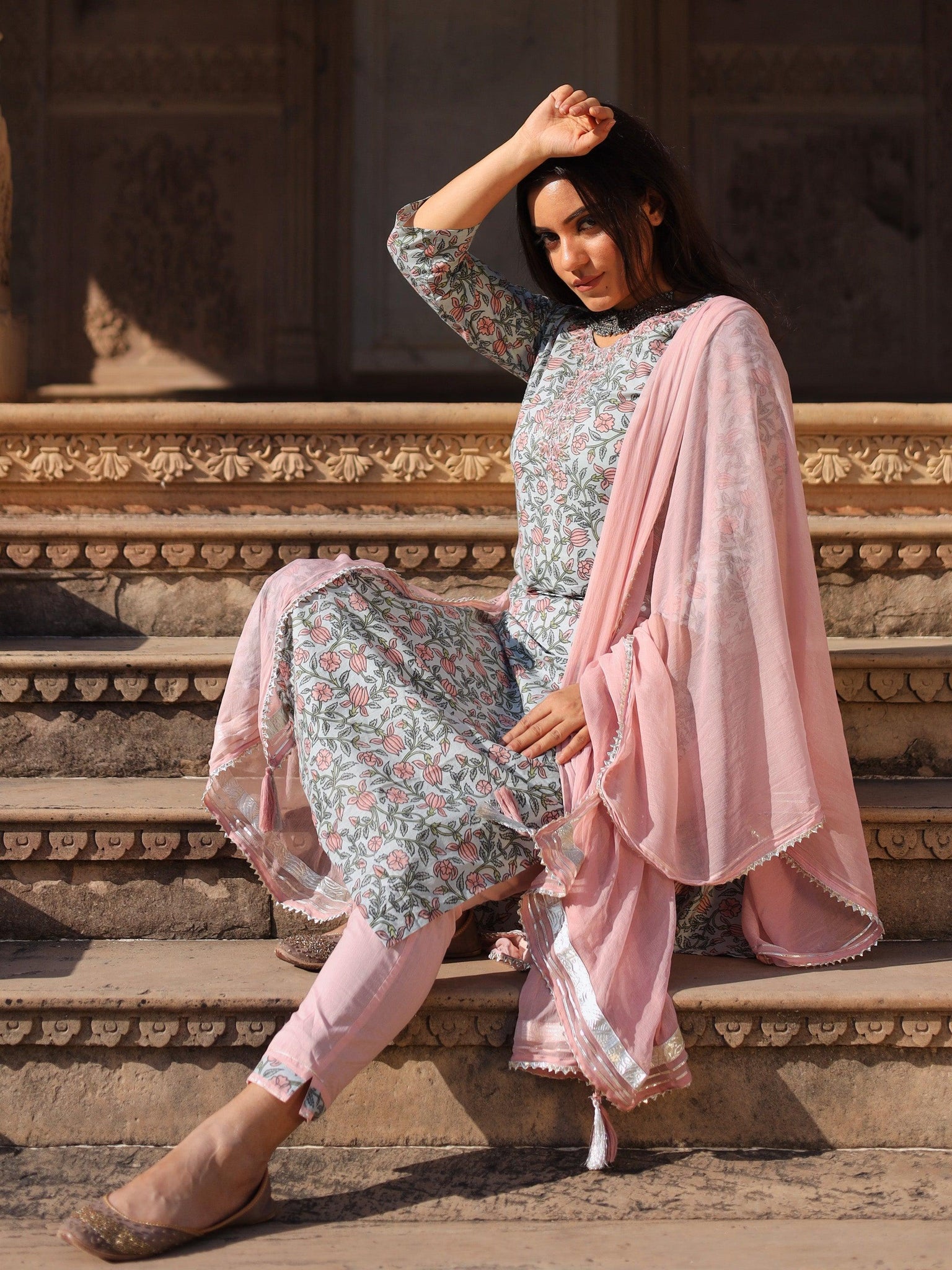 Woman wearing pastel blue floral straight cotton Kurta Pant set with dupatta on steps