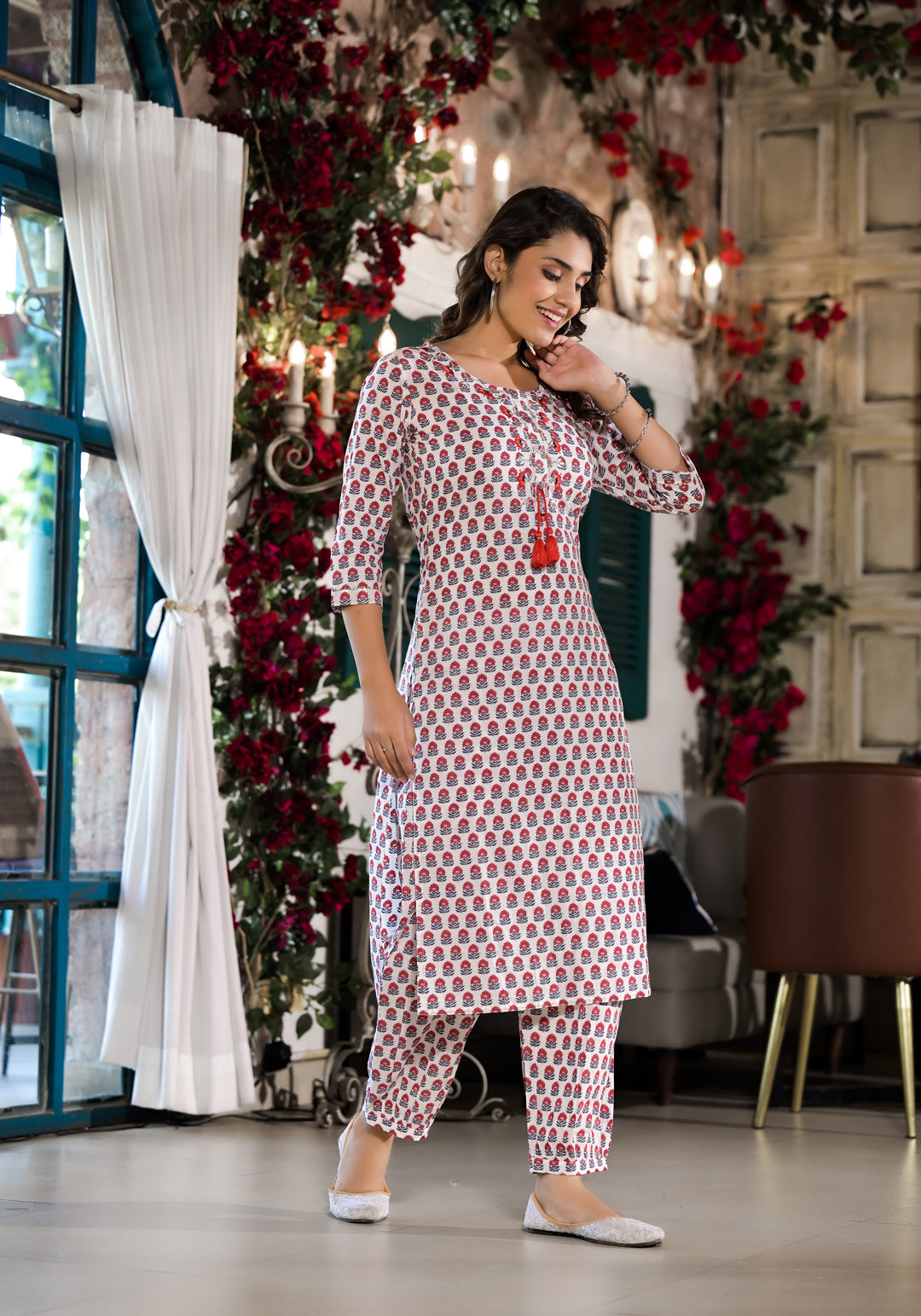 Woman in a red floral printed cotton kurta and trousers paired with white shoes