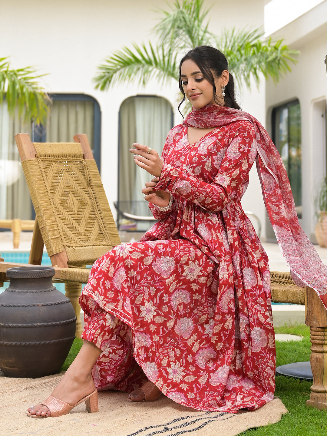 Woman in a vibrant floral printed red Cotton Alia Cut Kurta Set with matching scarf