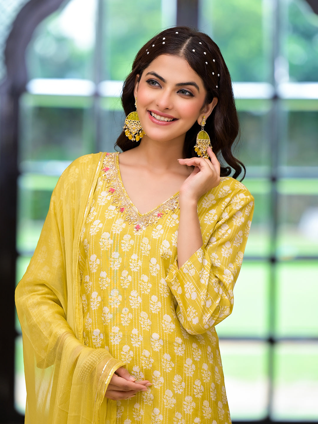 Woman in a bright yellow printed muslin straight kurta with gold embellishments