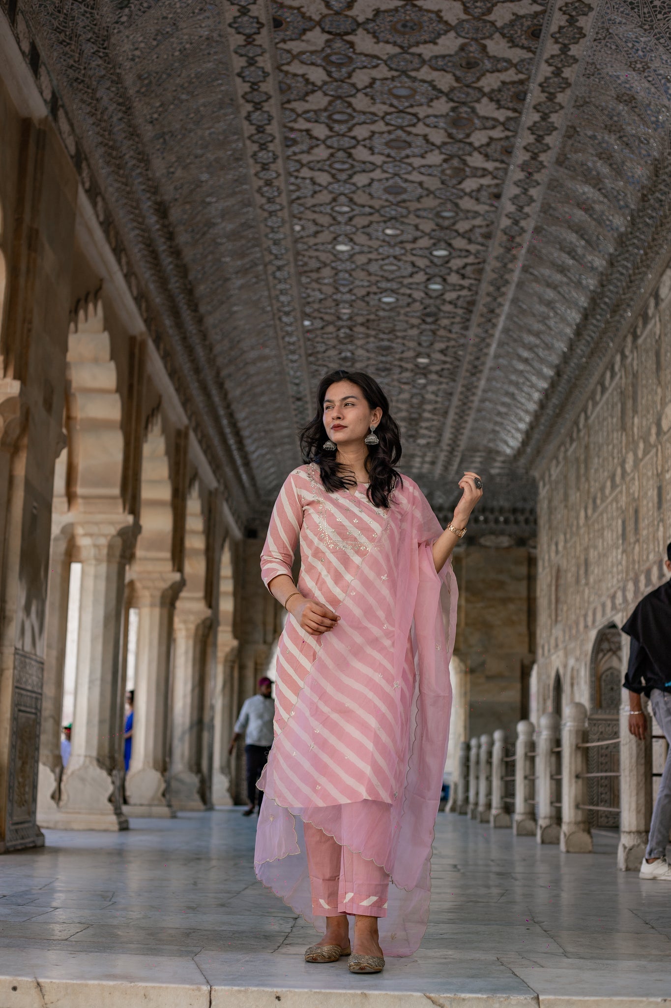 Woman in a Light Pink Leheriya Cotton Kurta with Organza Dupatta in ornate corridor