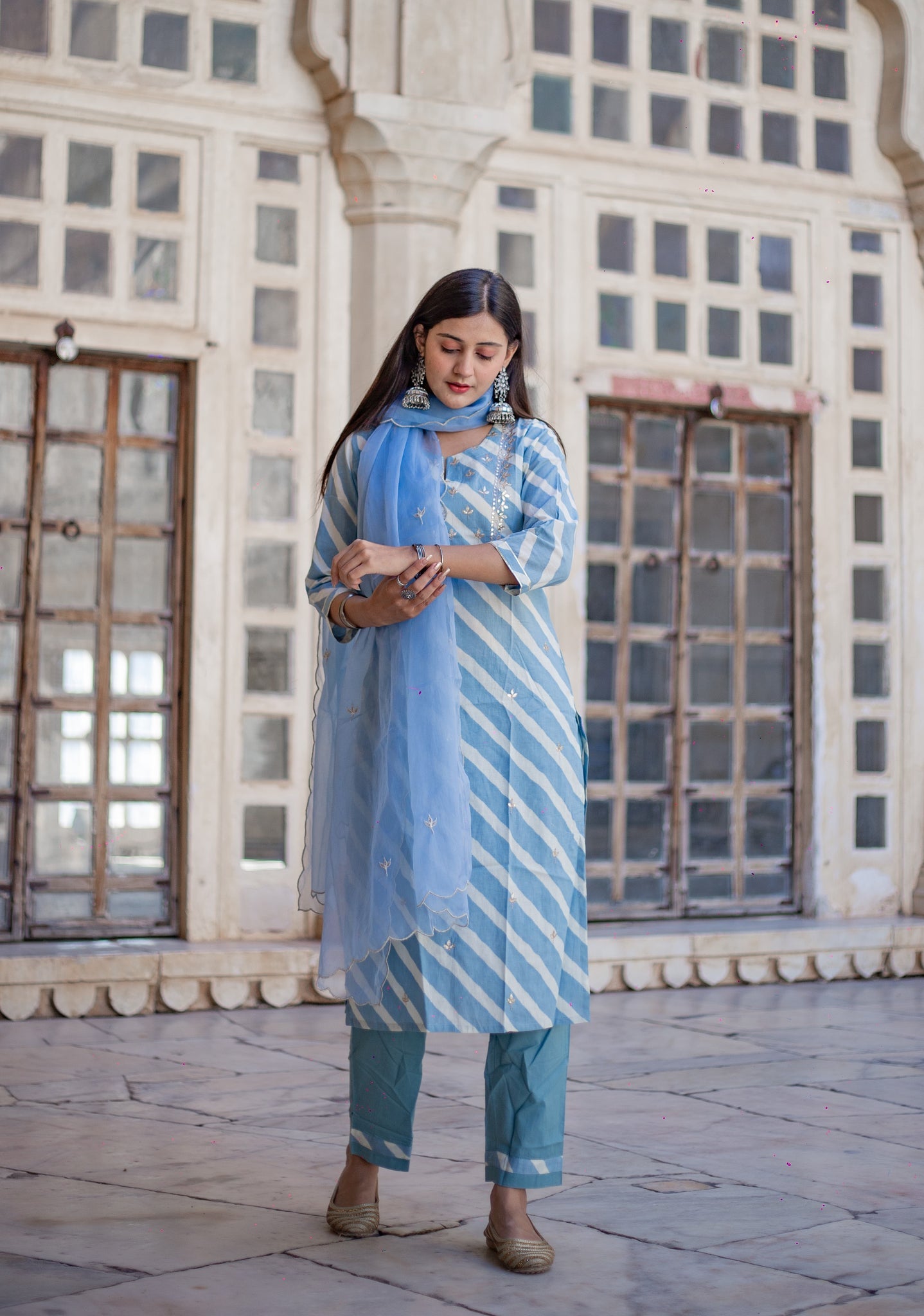 Woman in Sky Blue Leheriya Cotton Kurta with Organza Dupatta checking her mobile phone