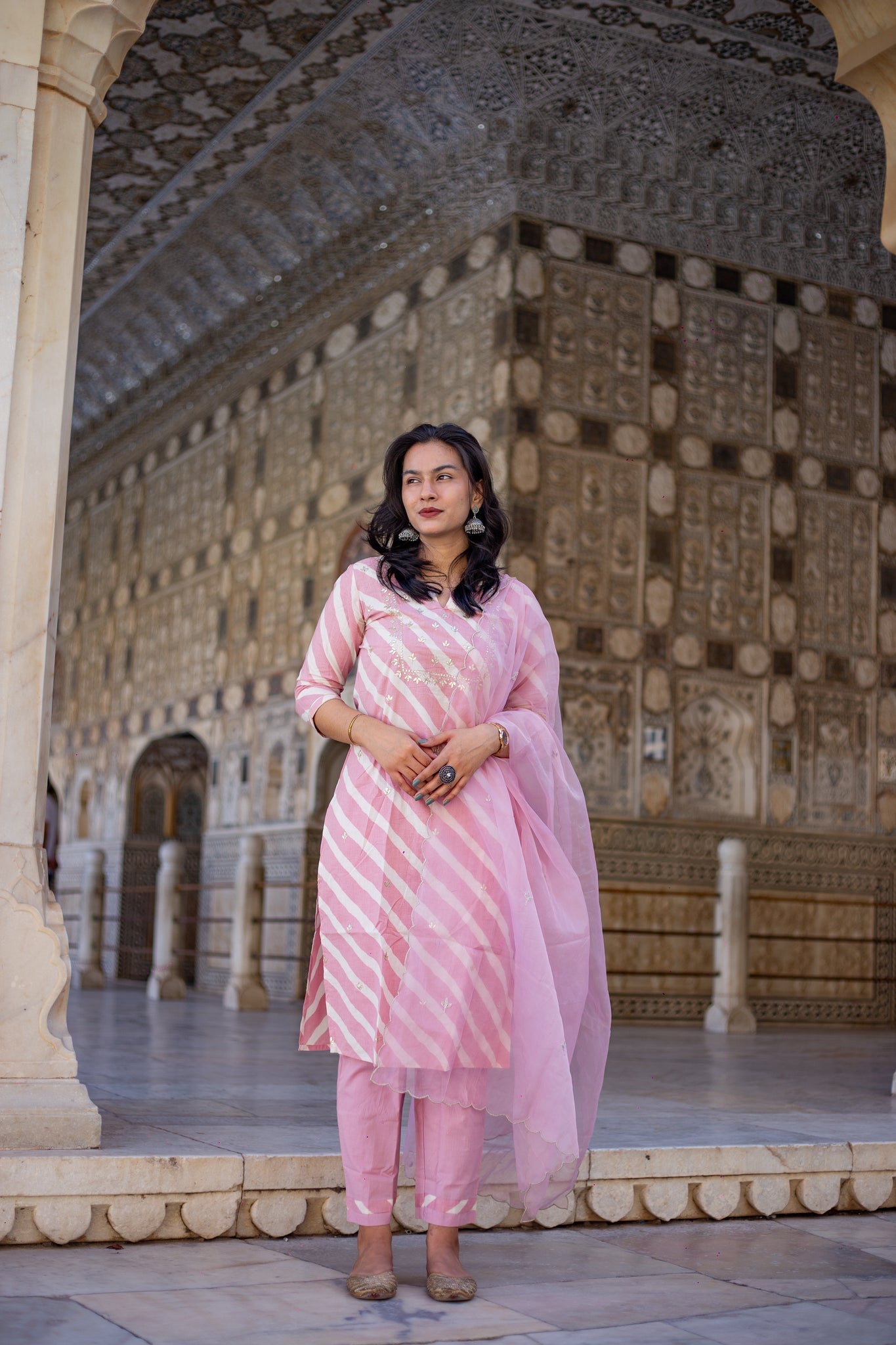 Woman in light pink leheriya cotton kurta with organza dupatta in ornate setting