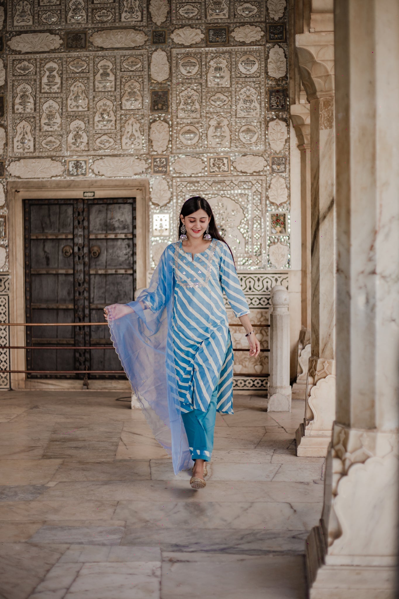 Woman in Sky Blue Leheriya Cotton Kurta with flowing Organza Dupatta and striped scarf